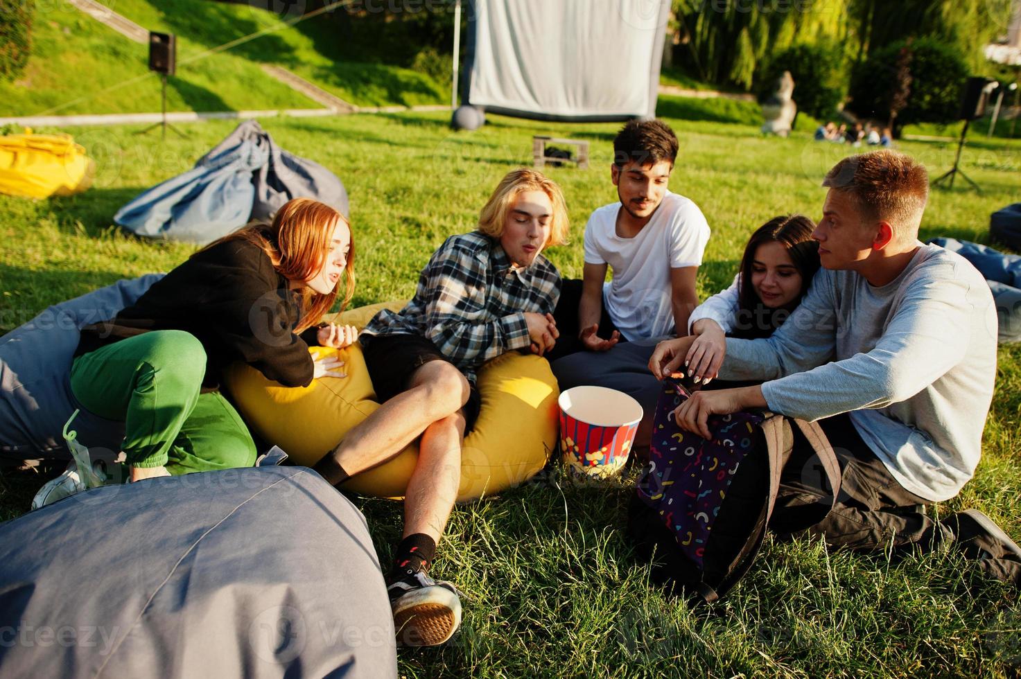 Young multi ethnic group of people watching movie at poof in open air cinema. photo