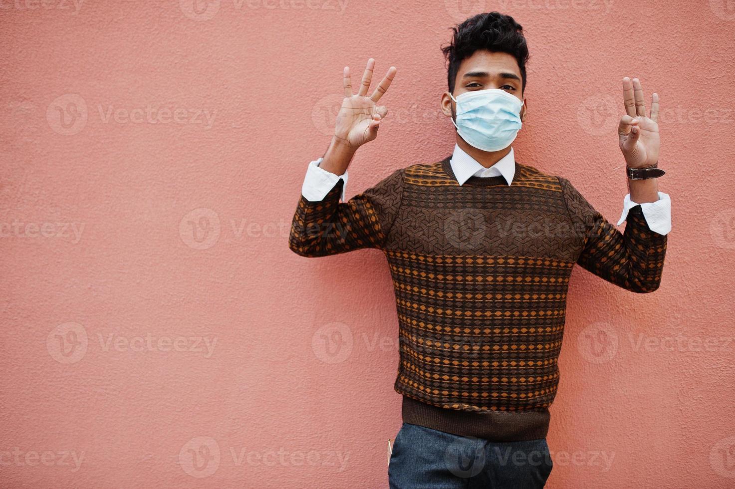 Coronavirus covid-19 concept. South asian indian man wearing mask for protect from corona virus isolated on pink background. photo