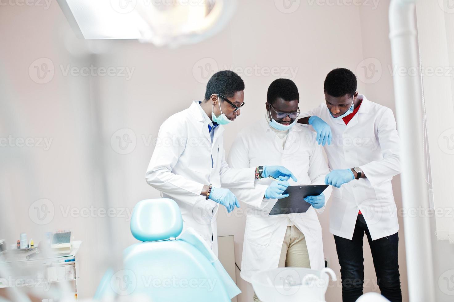 tres médicos afroamericanos trabajando, discutiendo con colegas en la clínica. foto