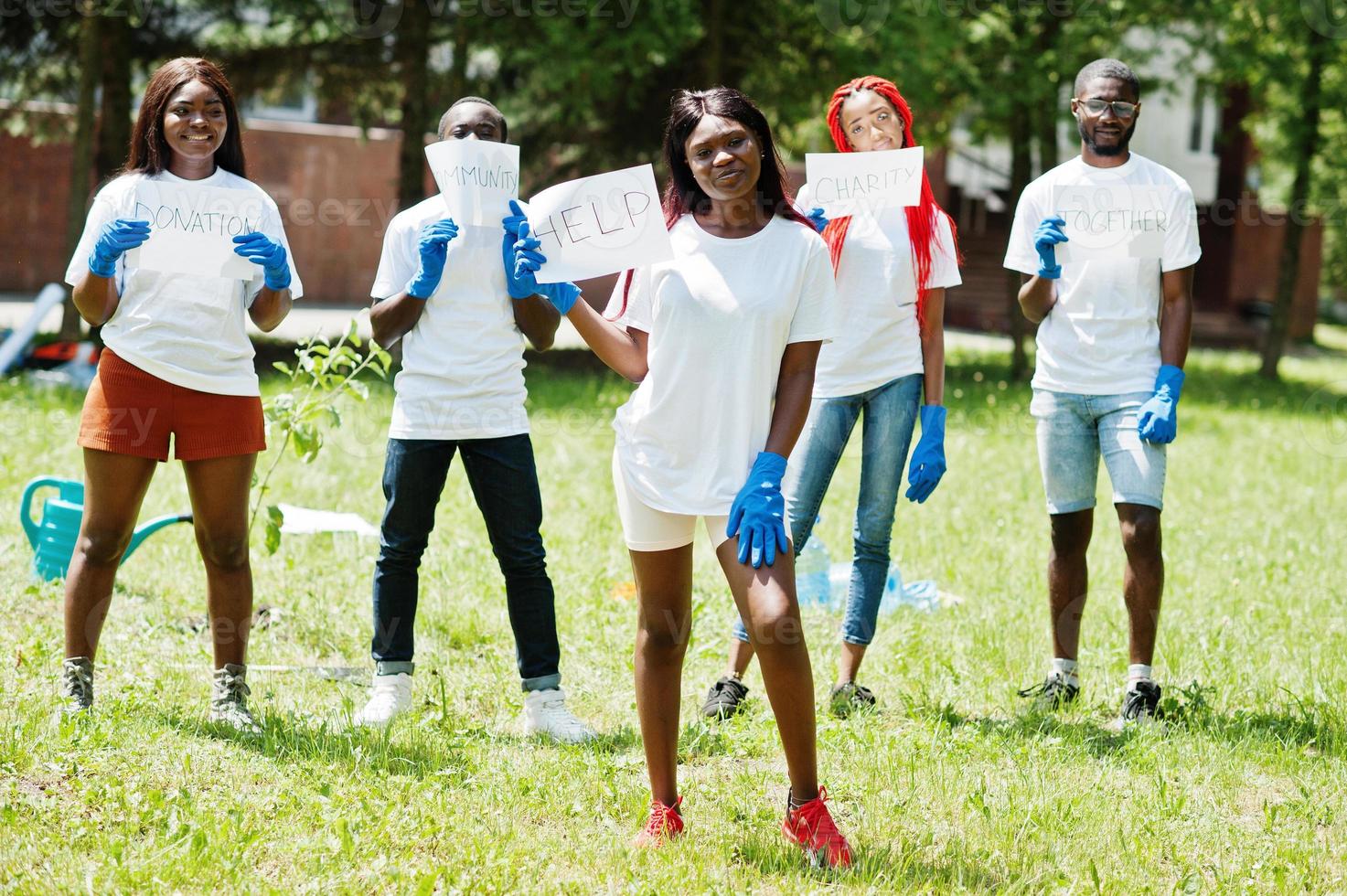 Group of happy african volunteers hold blank board with help sign in park. Africa volunteering, charity, people and ecology concept. photo