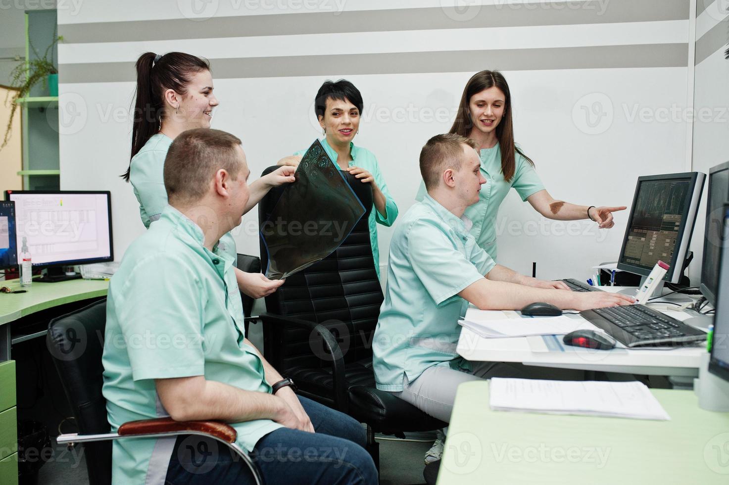 Medical theme.Observation room with a computer tomograph. The group of doctors meeting in the mri office at diagnostic center in hospital. Hold x-ray radiographic image. photo