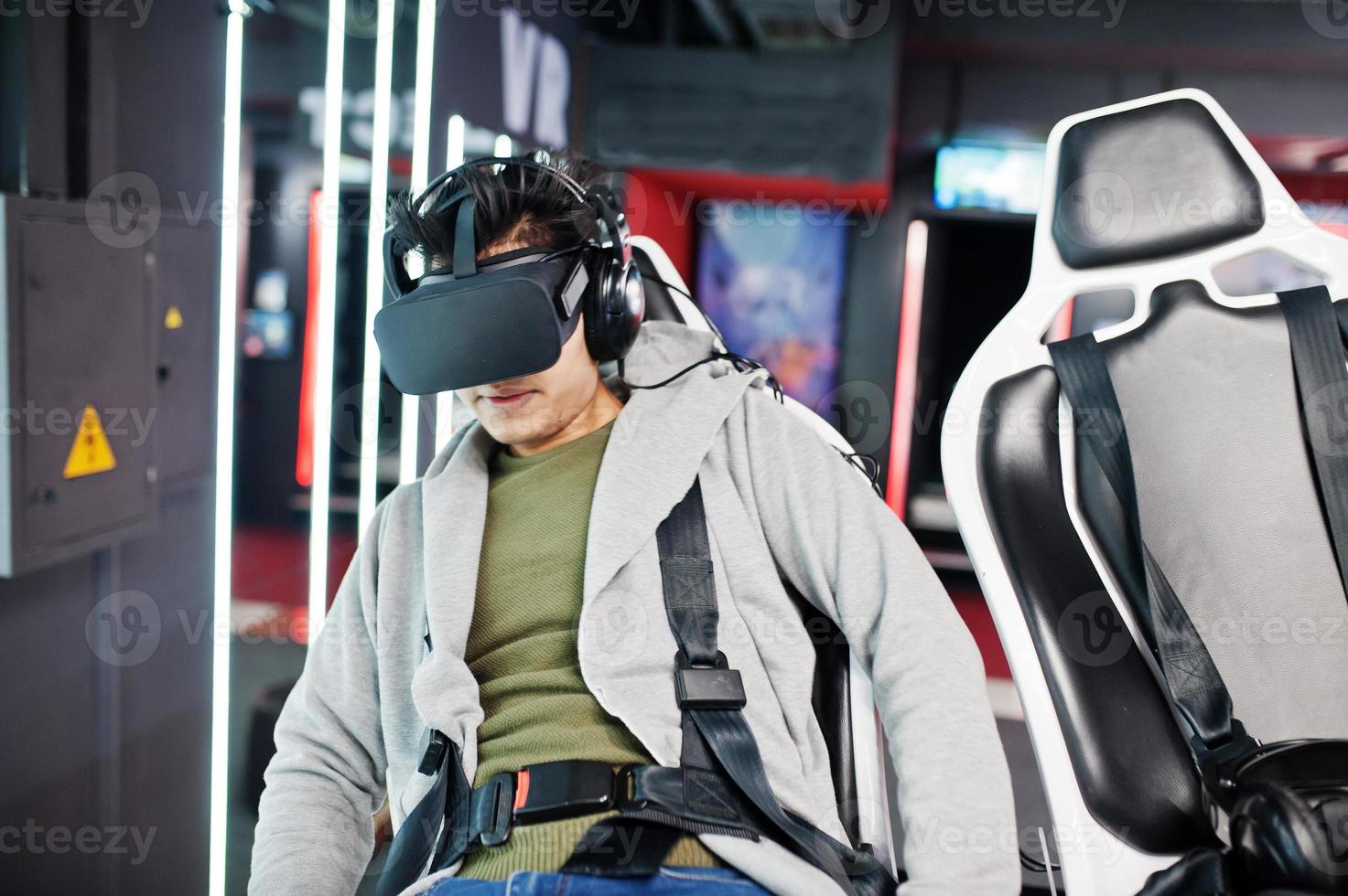 Young indian man having fun with a new technology of a vr headset at virtual reality simulator. photo