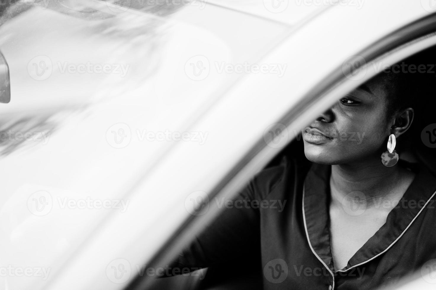 una rica mujer africana de negocios se sienta en el asiento del conductor en un camión todoterreno plateado con la puerta abierta. foto