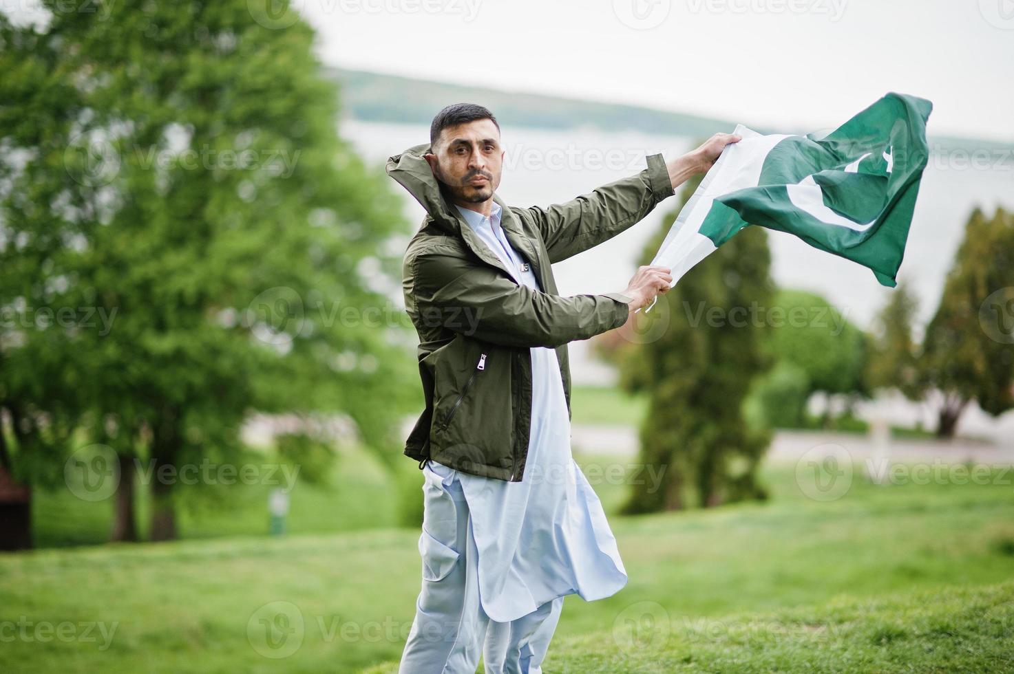 ropa tradicional retrato masculino pakistaní indio sostiene la bandera de pakistán. foto