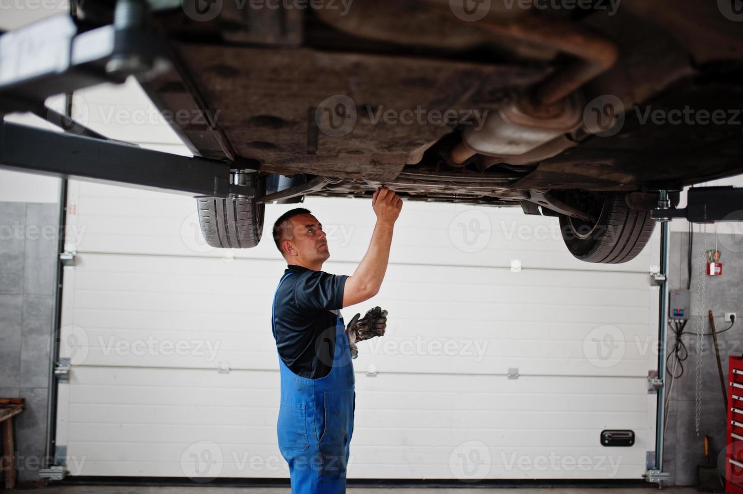 Car repair and maintenance theme. Mechanic in uniform working in auto service. photo