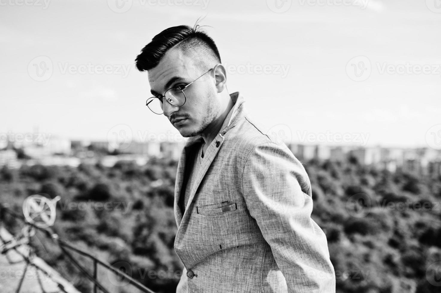 Dreamer stylish macho man in gray suit and glasses posed on the roof. photo