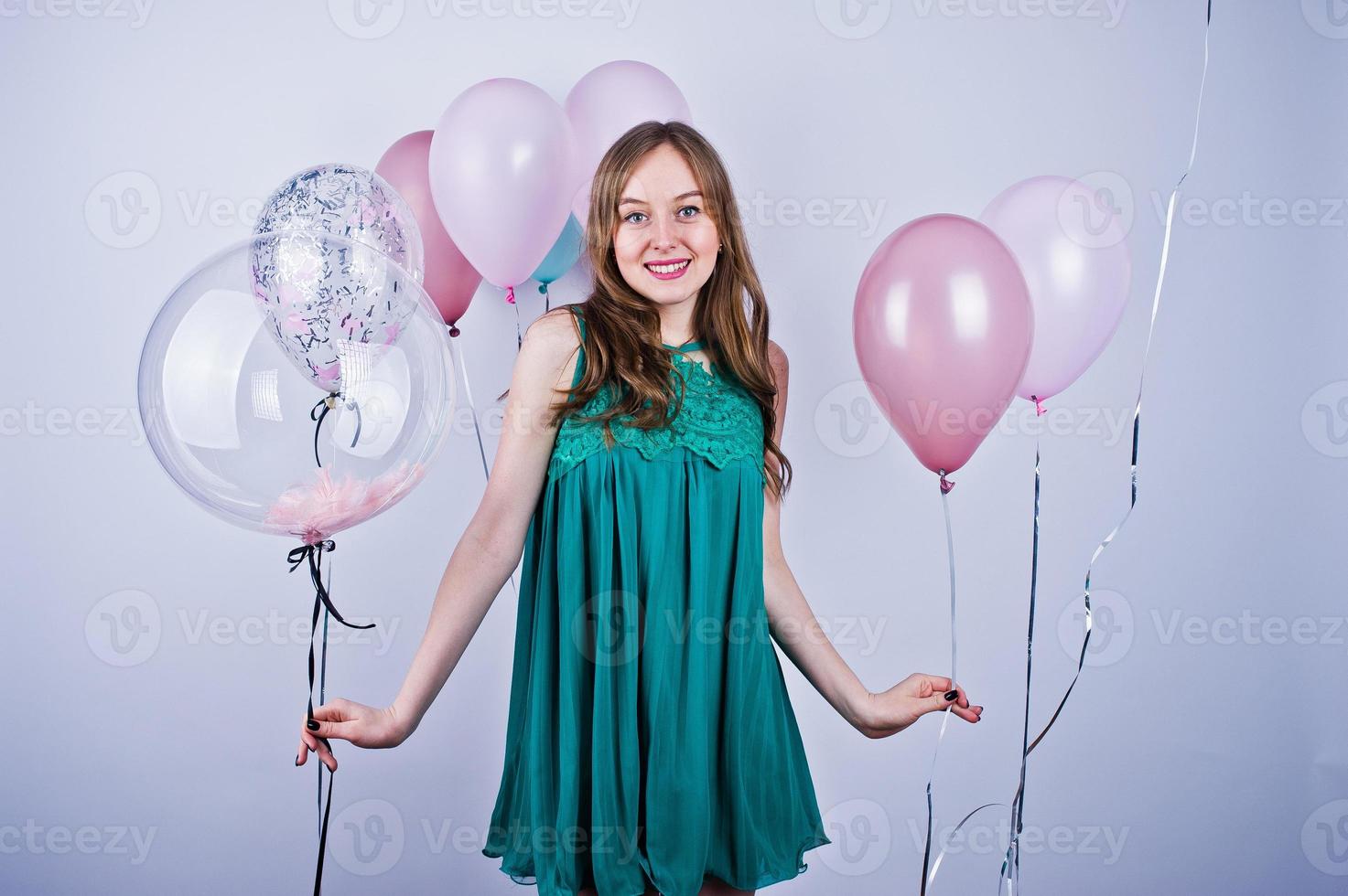 Happy girl in green turqoise dress with colored balloons isolated on white. Celebrating birthday theme. photo