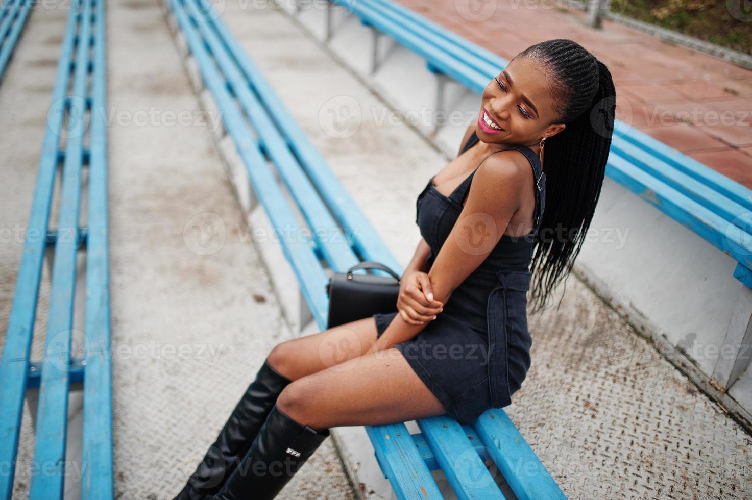 joven elegante sexy hermosa mujer afroamericana en la calle en las gradas del estadio, vestida de negro. foto