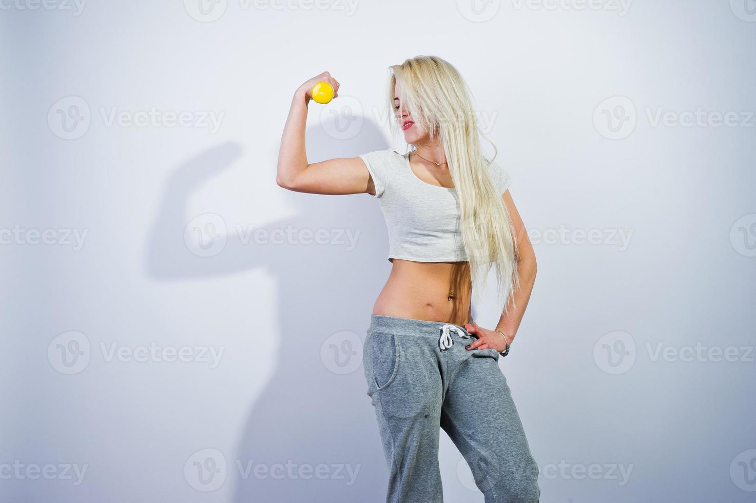 Blonde sporty girl with yellow dumbbell posed at studio against white background. photo