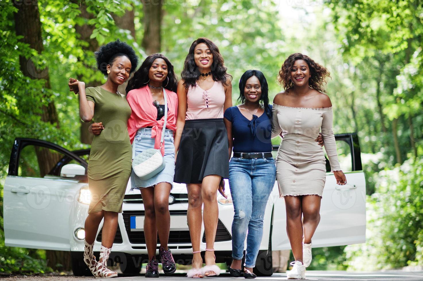 Group of five happy african american walking against white car. photo