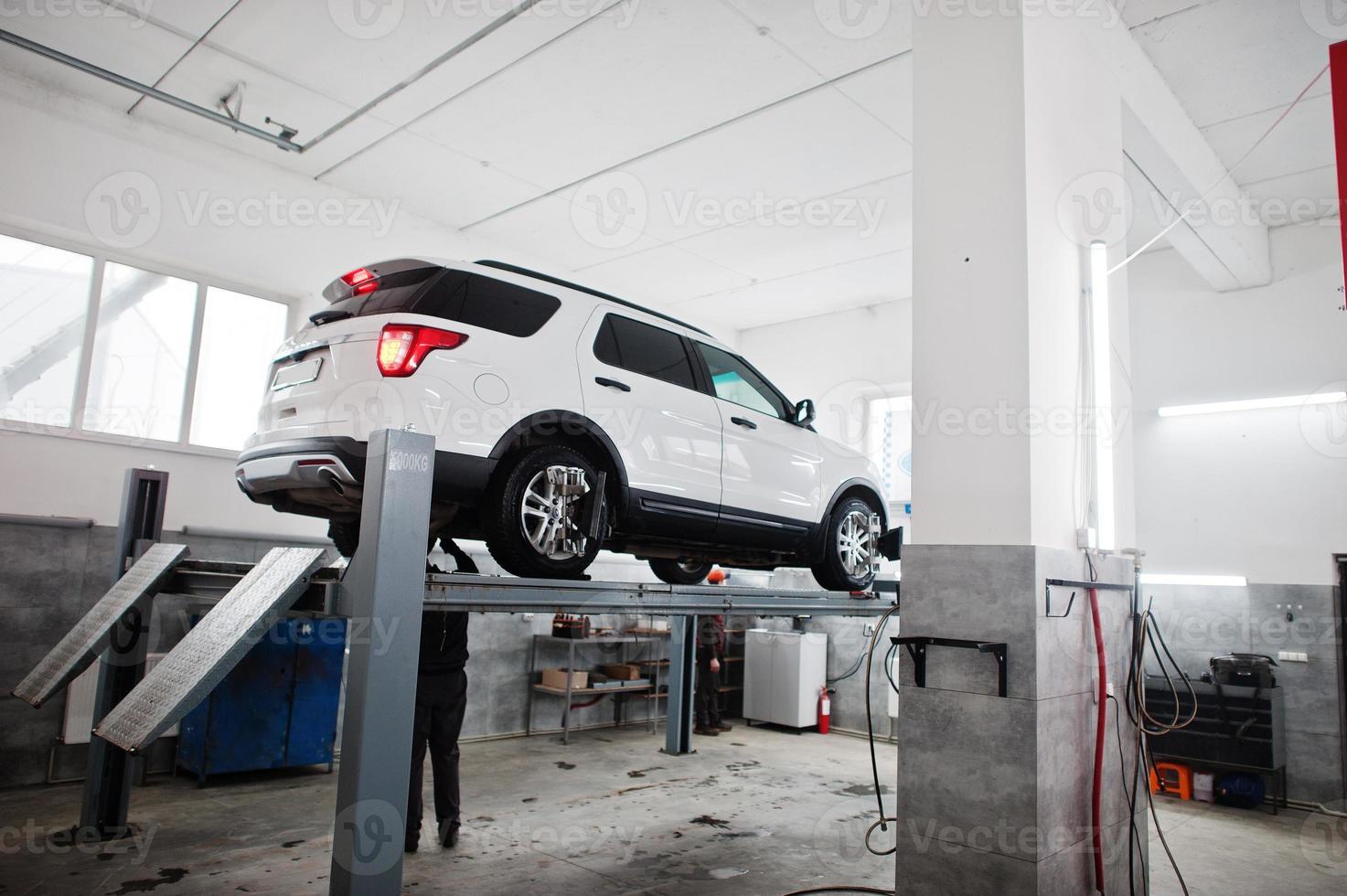 American SUV car on stand for wheels alignment camber check in workshop of service station. photo