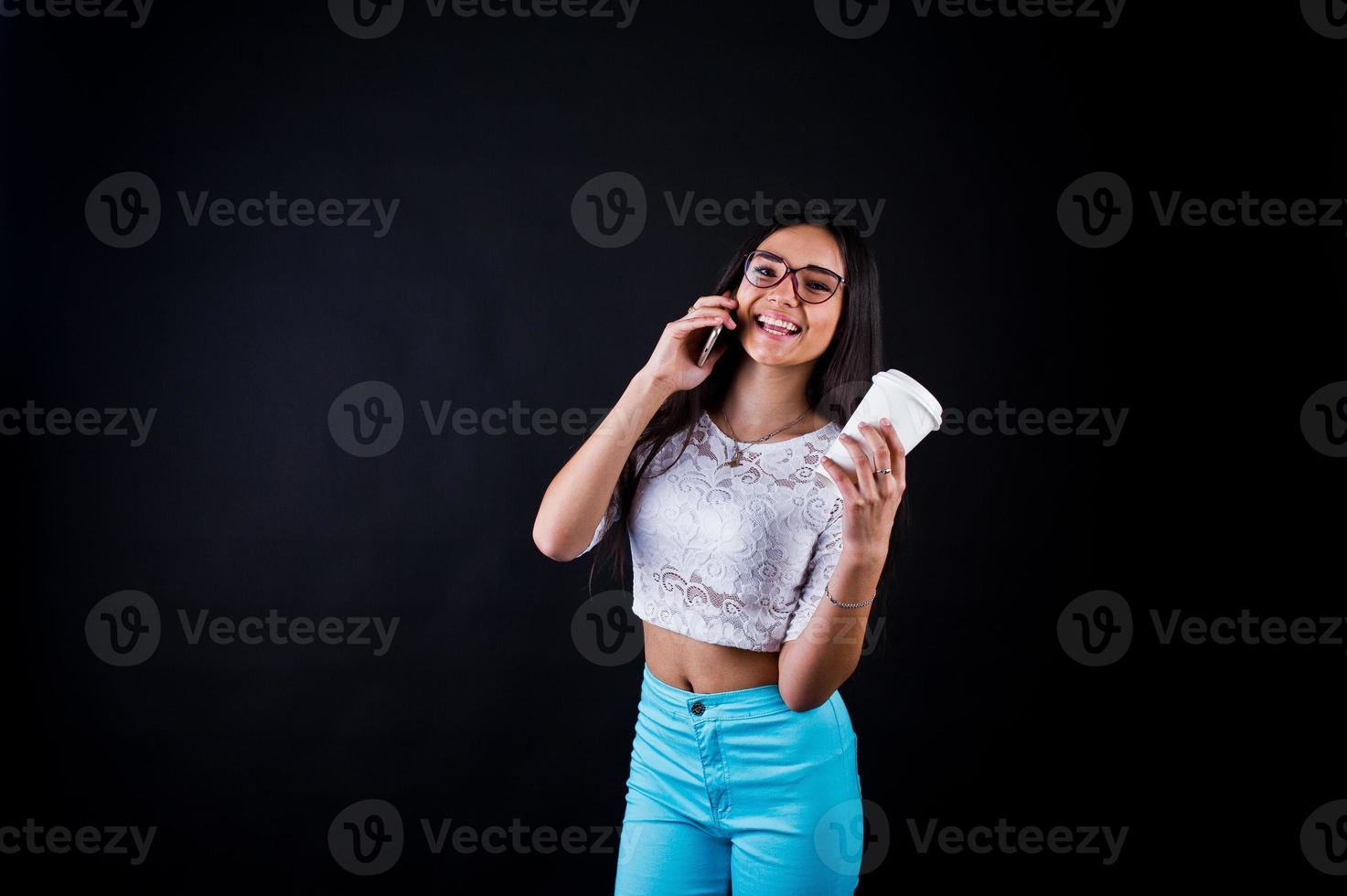 Portrait of a young happy woman in white top and blue trousers with a cup of coffee in her hand. photo