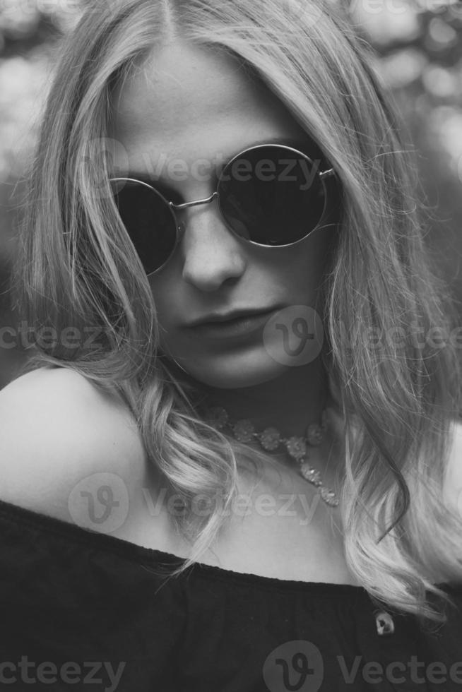 Woman in black round sunglasses in black and white photo