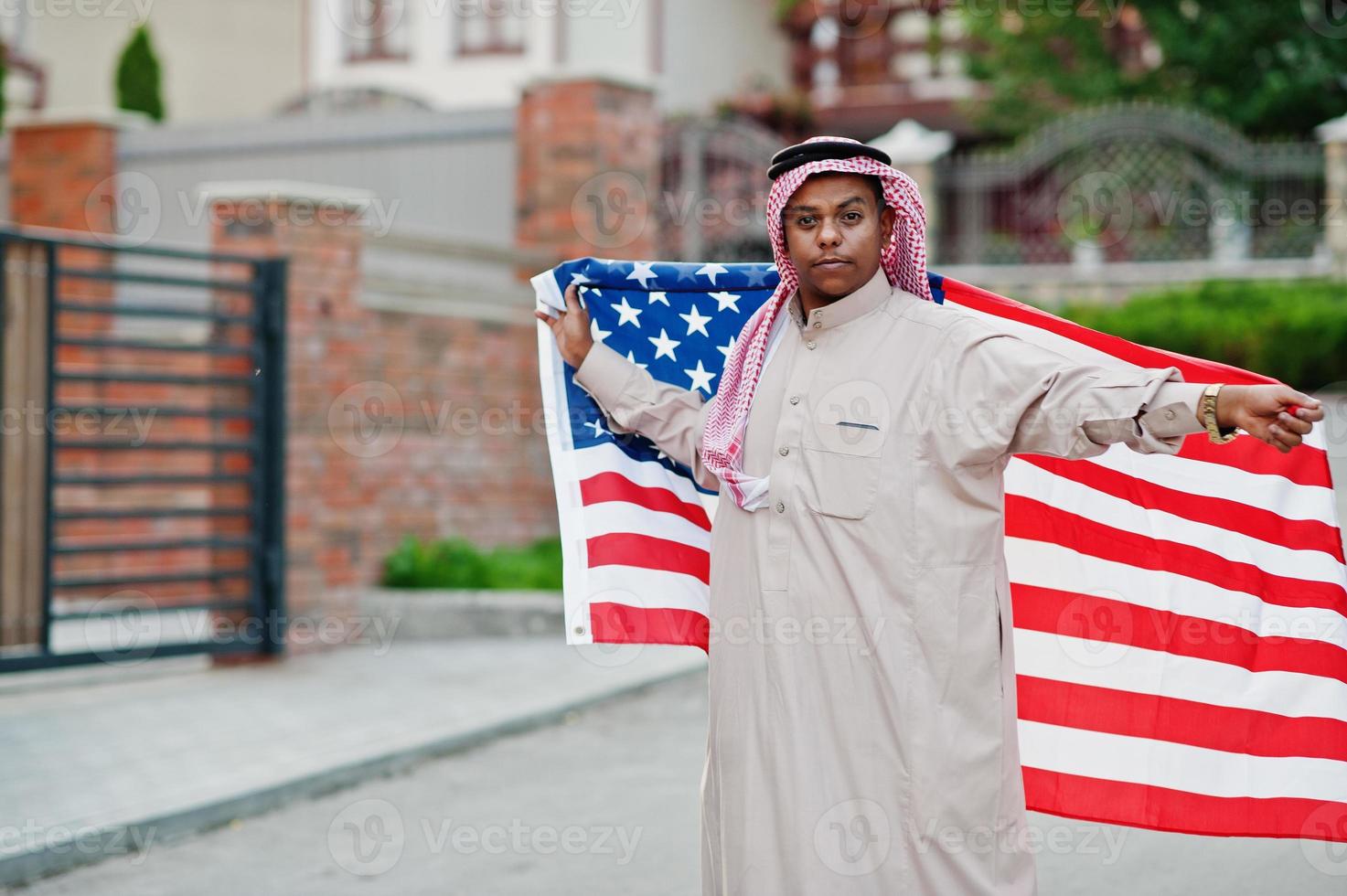 Middle Eastern arab man posed on street with USA flag. America and Arabian countries concept. photo