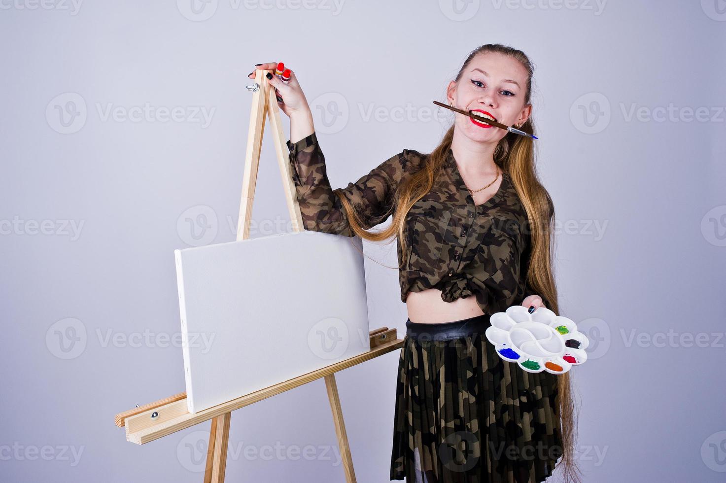 Beautiful woman artist painter with brushes and oil canvas posing in studio isolated on white. photo