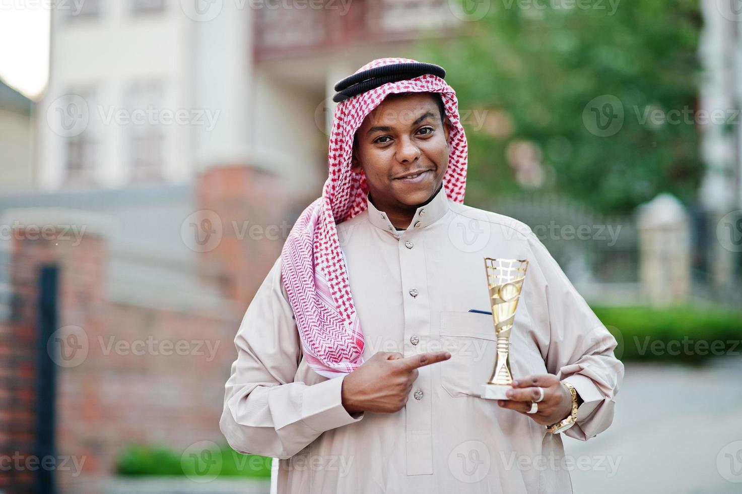 hombre de negocios árabe del medio oriente posó en la calle con una copa de oro en las manos. foto