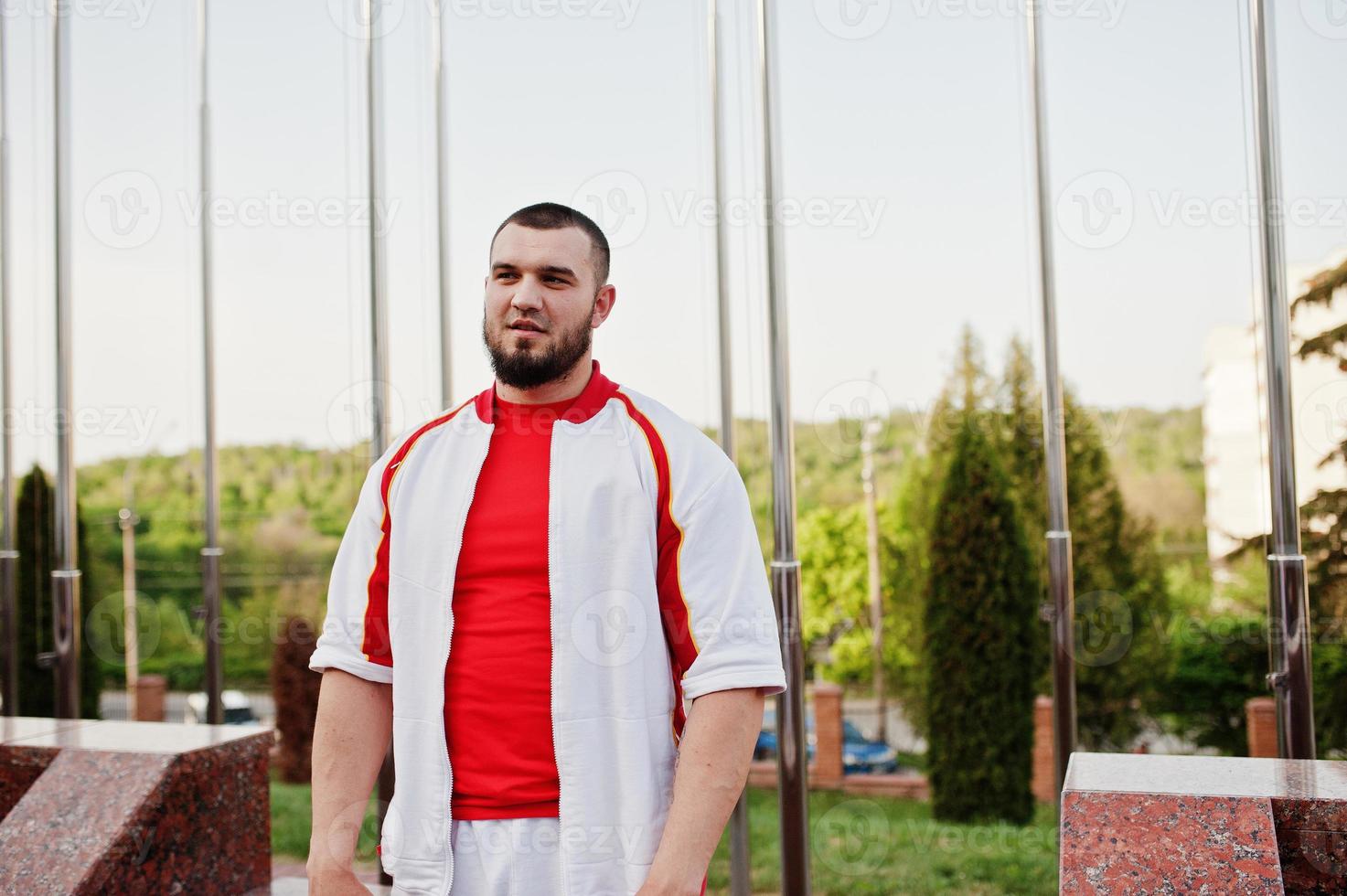 Young brutal bearded muscular man wear on white sport suit with red shirt. photo
