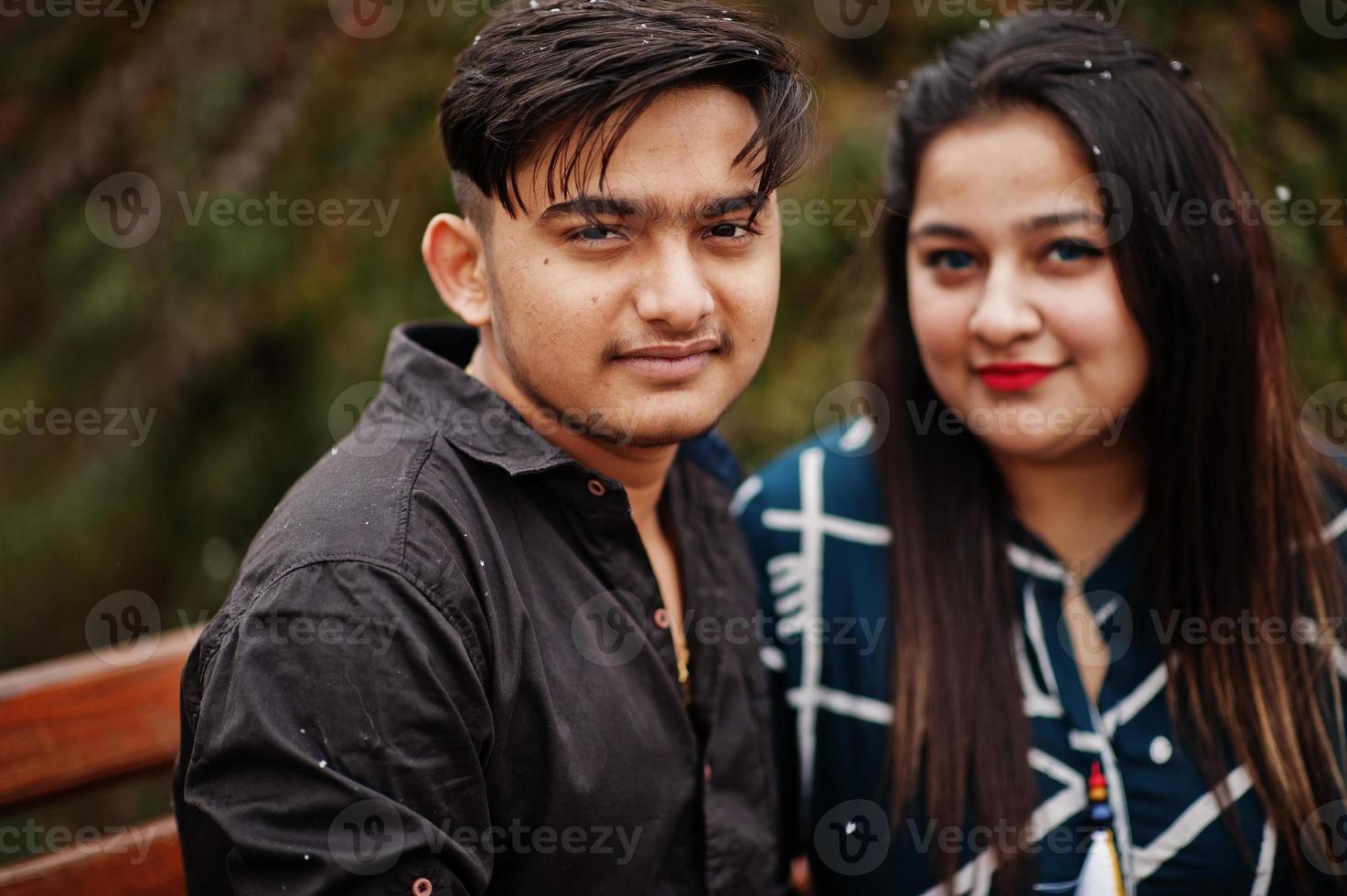 Love story of indian couple posed outdoor, sitting on bench together. photo