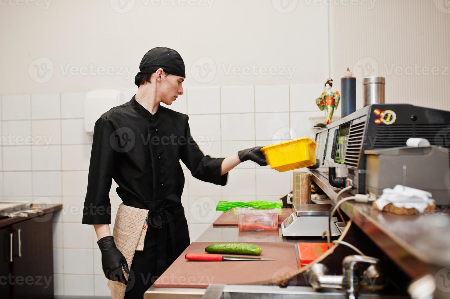 Professional chef wear in black making sushi and rolls in a restaurant kitchen of japanese traditional food. photo