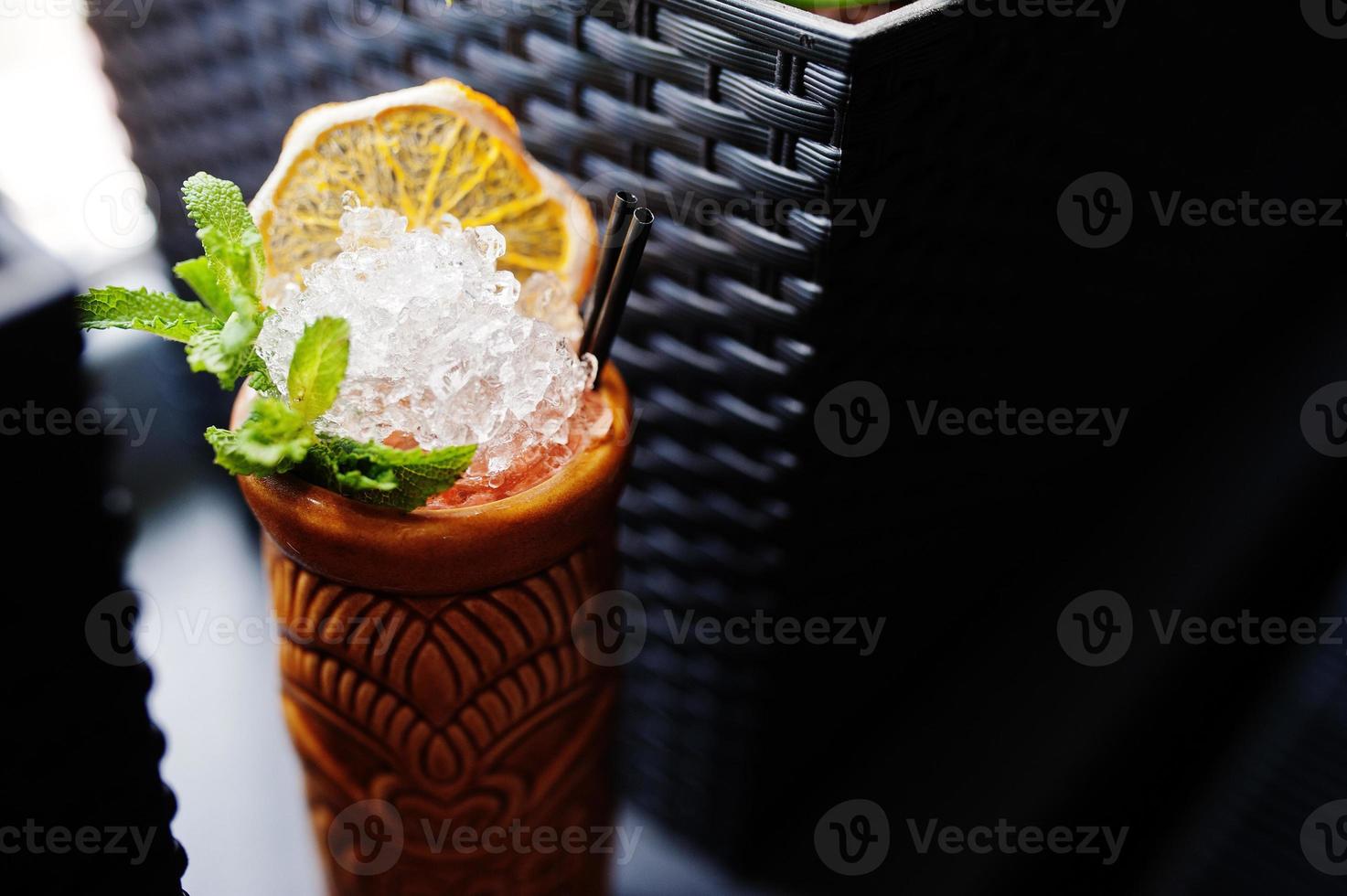 Alcoholic cocktail with mint in originally voodoo earthen glass on bar table. photo