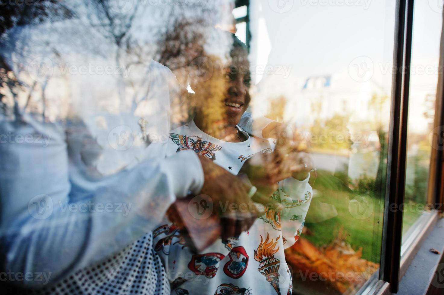 Happy african friends chatting in cafe. Group of black peoples meeting in restaurant against glass of window. photo