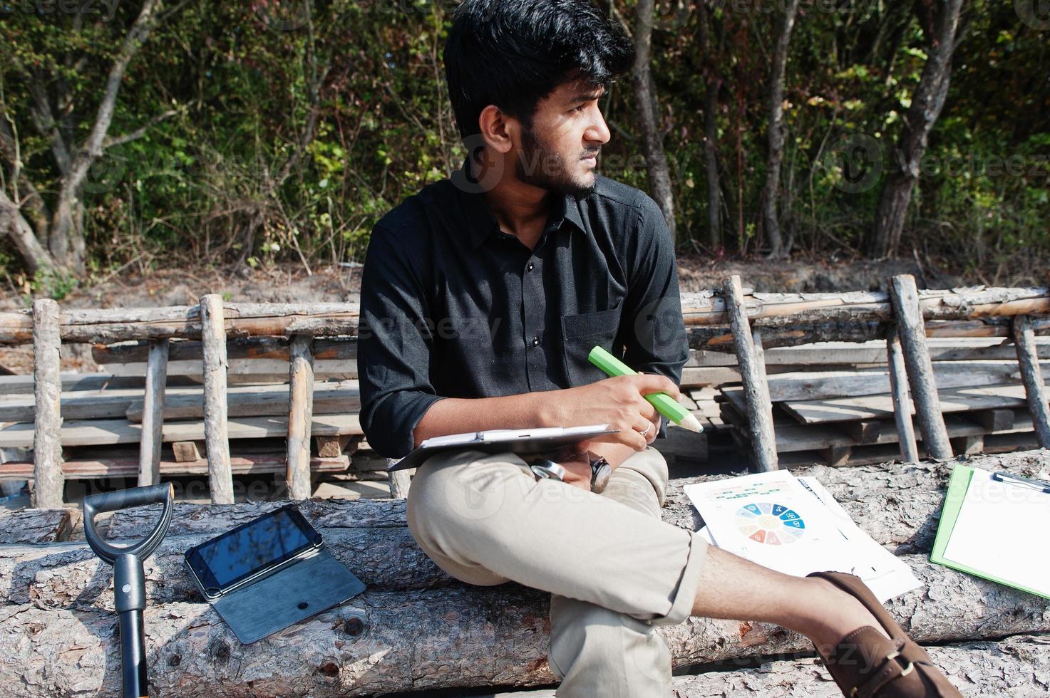 South asian agronomist farmer looking at diagram papers on farm. Agriculture production concept. photo