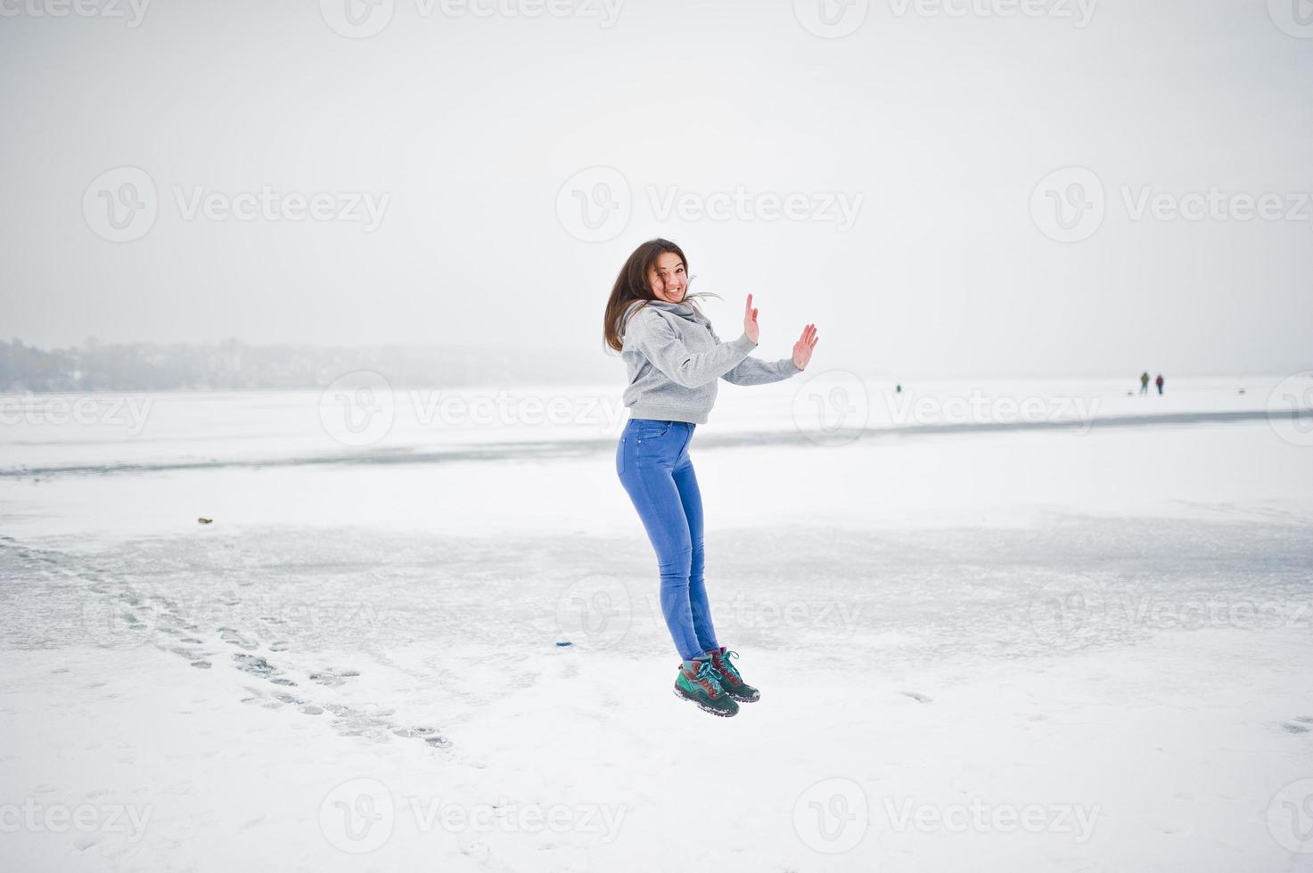 Funny jumping girl on frozen lake in winter day. photo