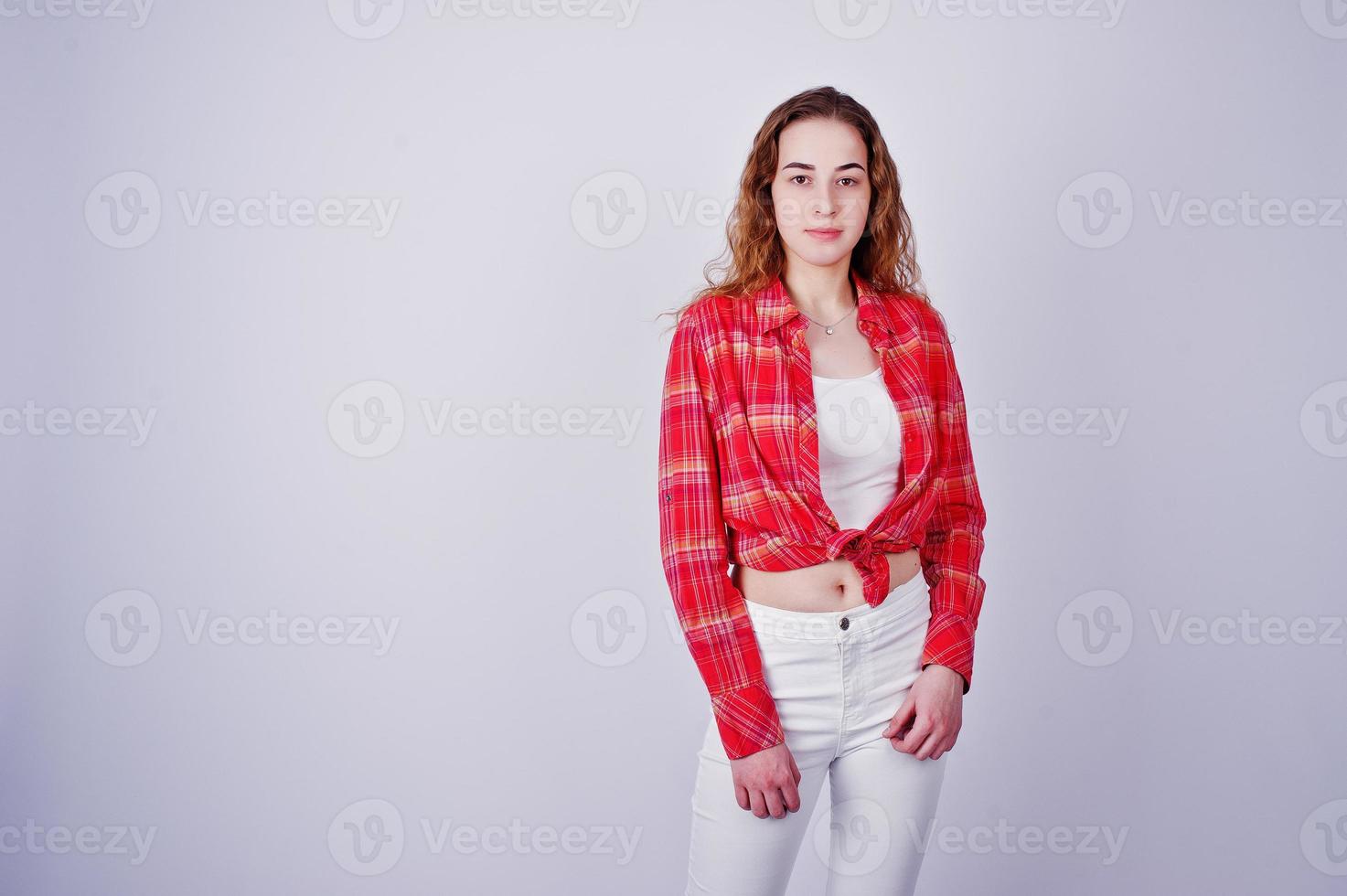 Young girl in red checked shirt and white pants against white background on studio. photo