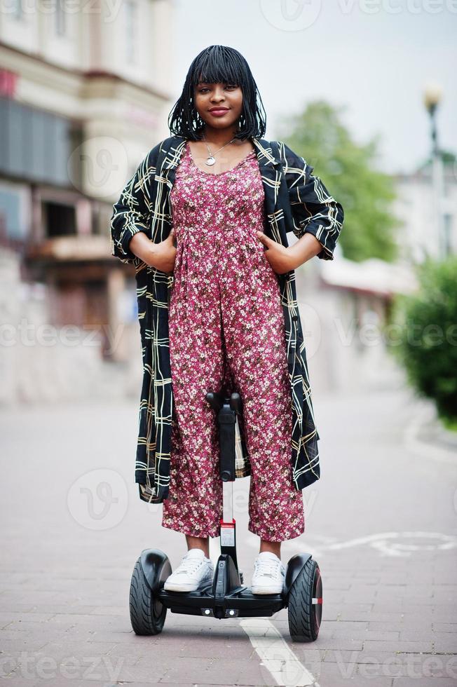 Beautiful african american woman using segway or hoverboard. Black girl on dual wheel self balancing electrical scooter. photo