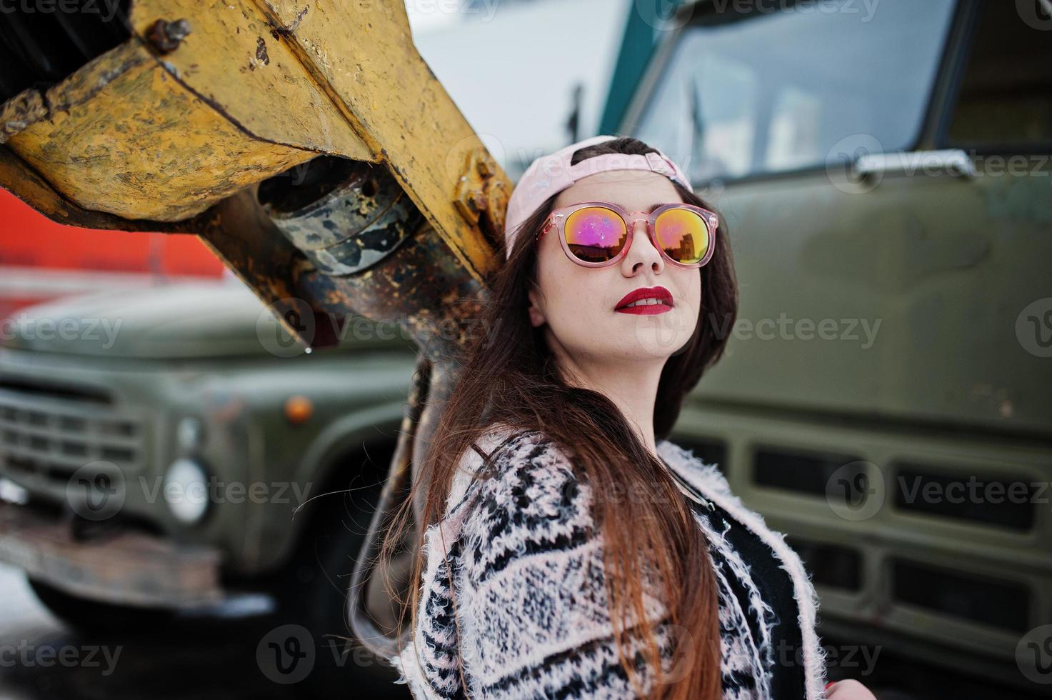 chica casual con estilo morena en gorra contra grúa de camión viejo. foto