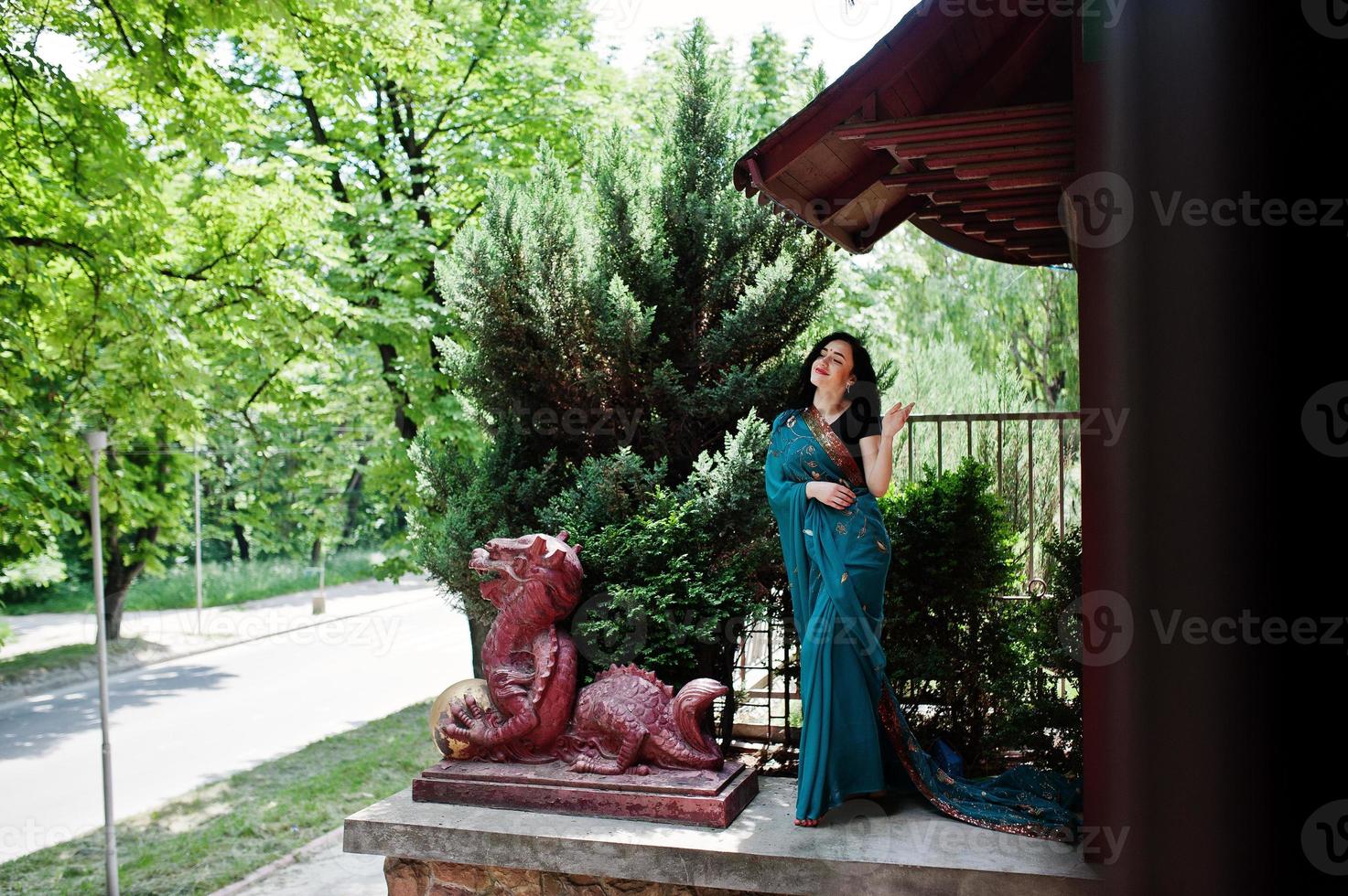 Portrait of beautiful indian brumette girl or hindu woman model against japanese traditional house and dragon figure. photo