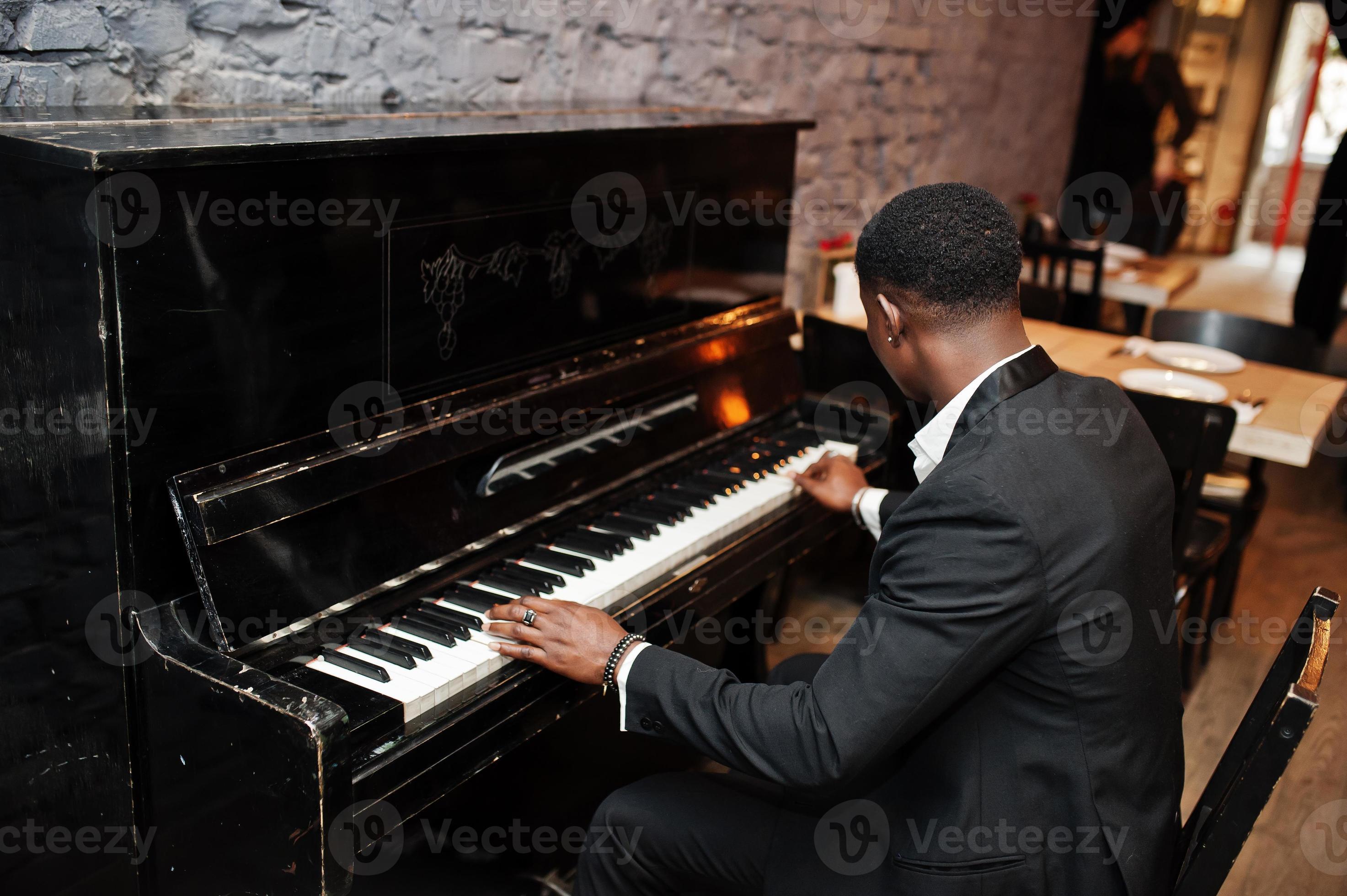 Back of strong powerful african american man in black suit play piano