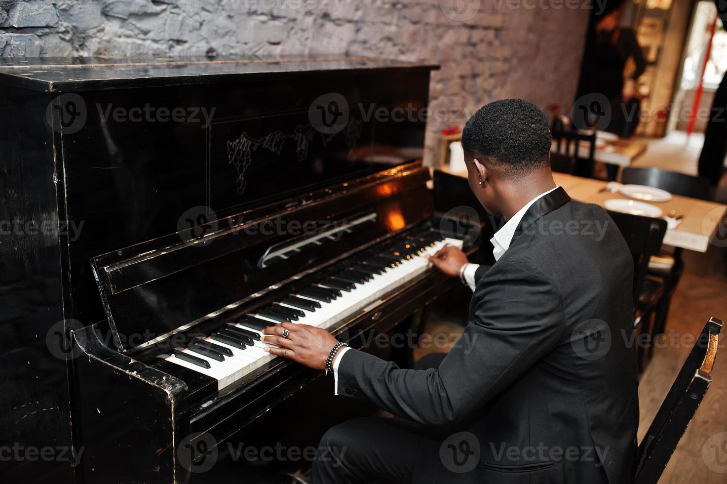 Back of strong powerful african american man in black suit play piano