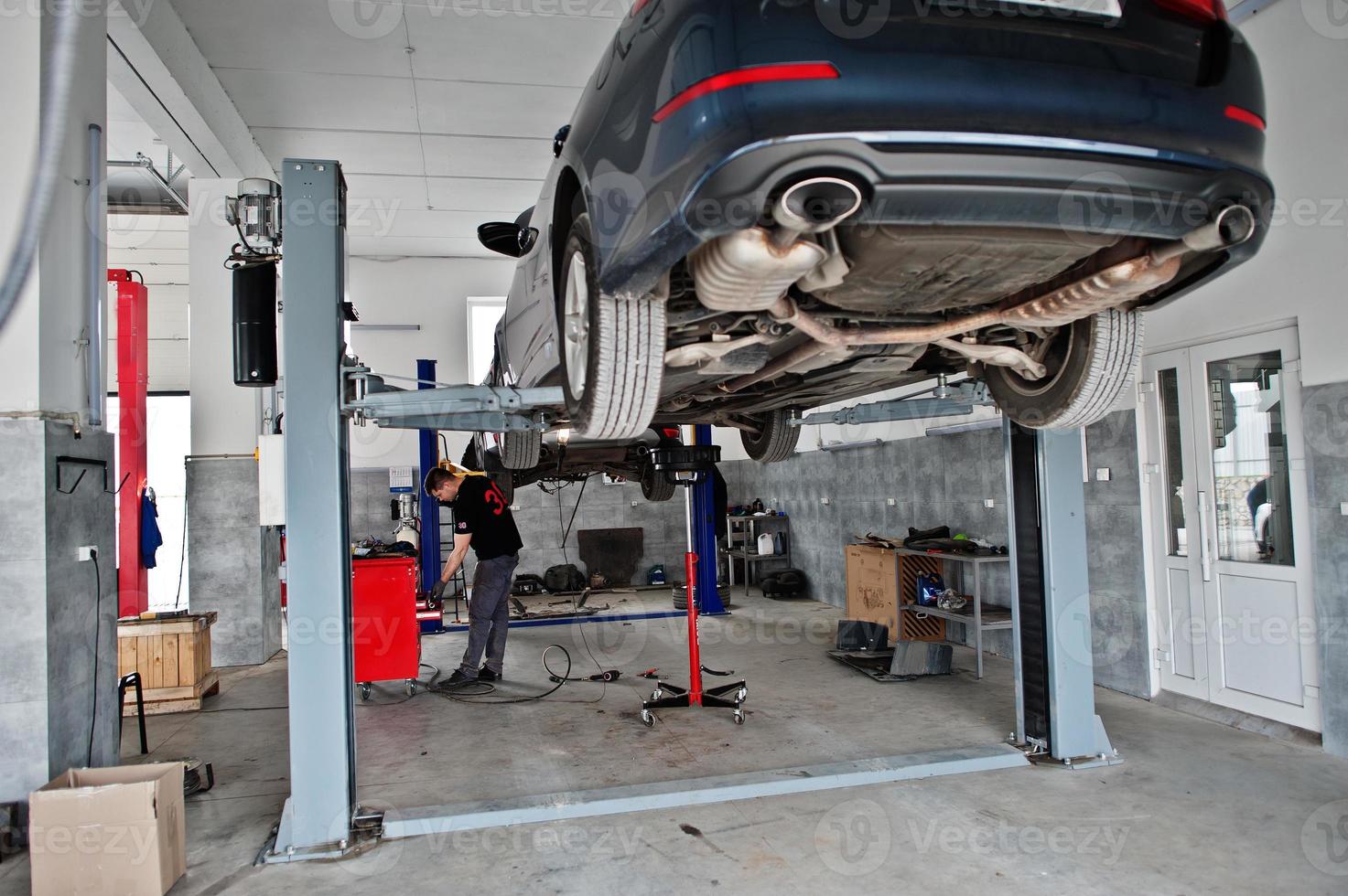 Car repair and maintenance theme. Mechanic in uniform working in auto service. photo