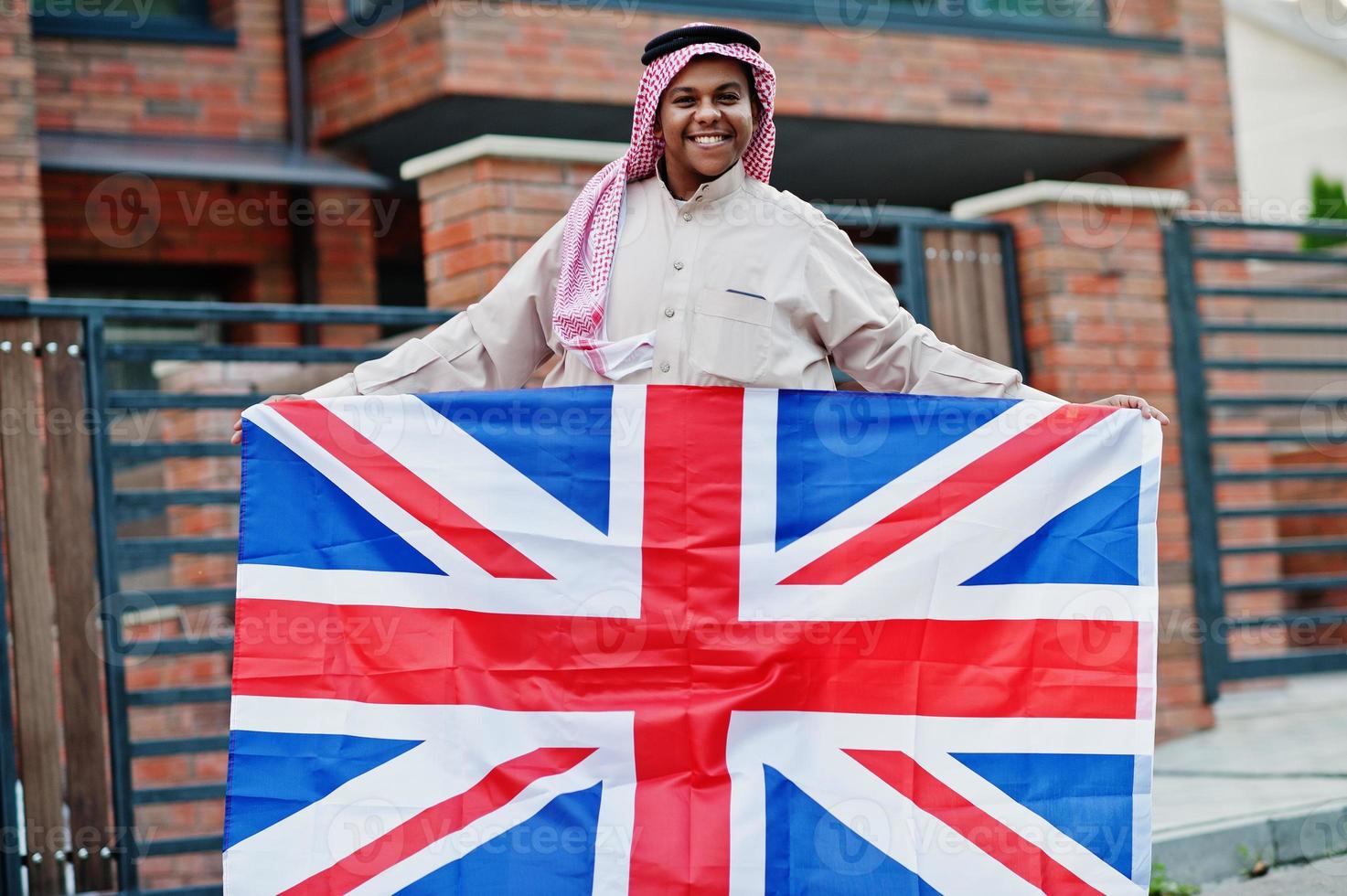 Middle Eastern arab man posed on street with Great Britain flag. England and Arabian countries concept. photo