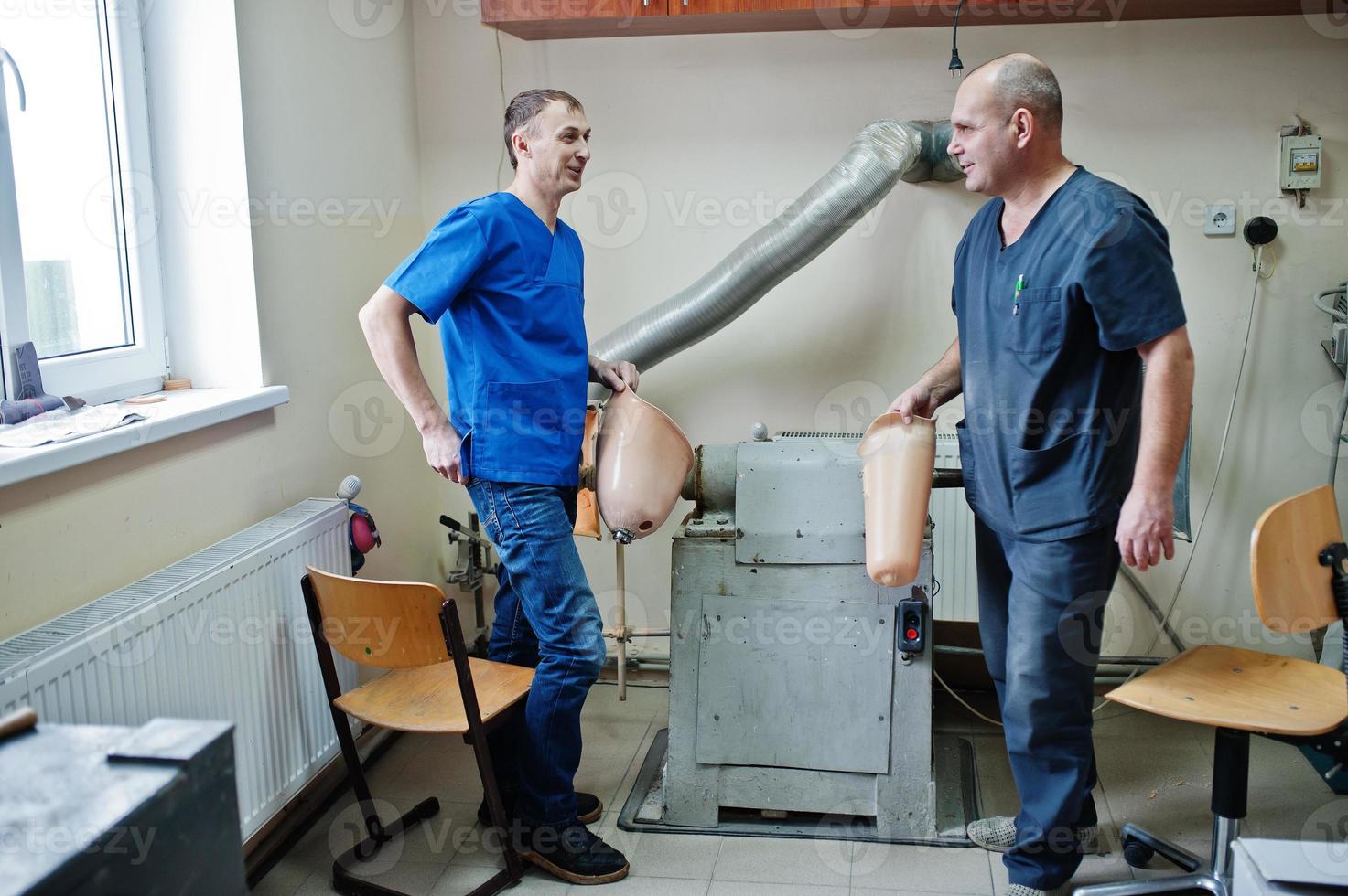 Two prosthetist man workers making prosthetic leg while working in laboratory. photo
