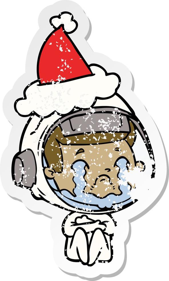 distressed sticker cartoon of a crying astronaut wearing santa hat vector