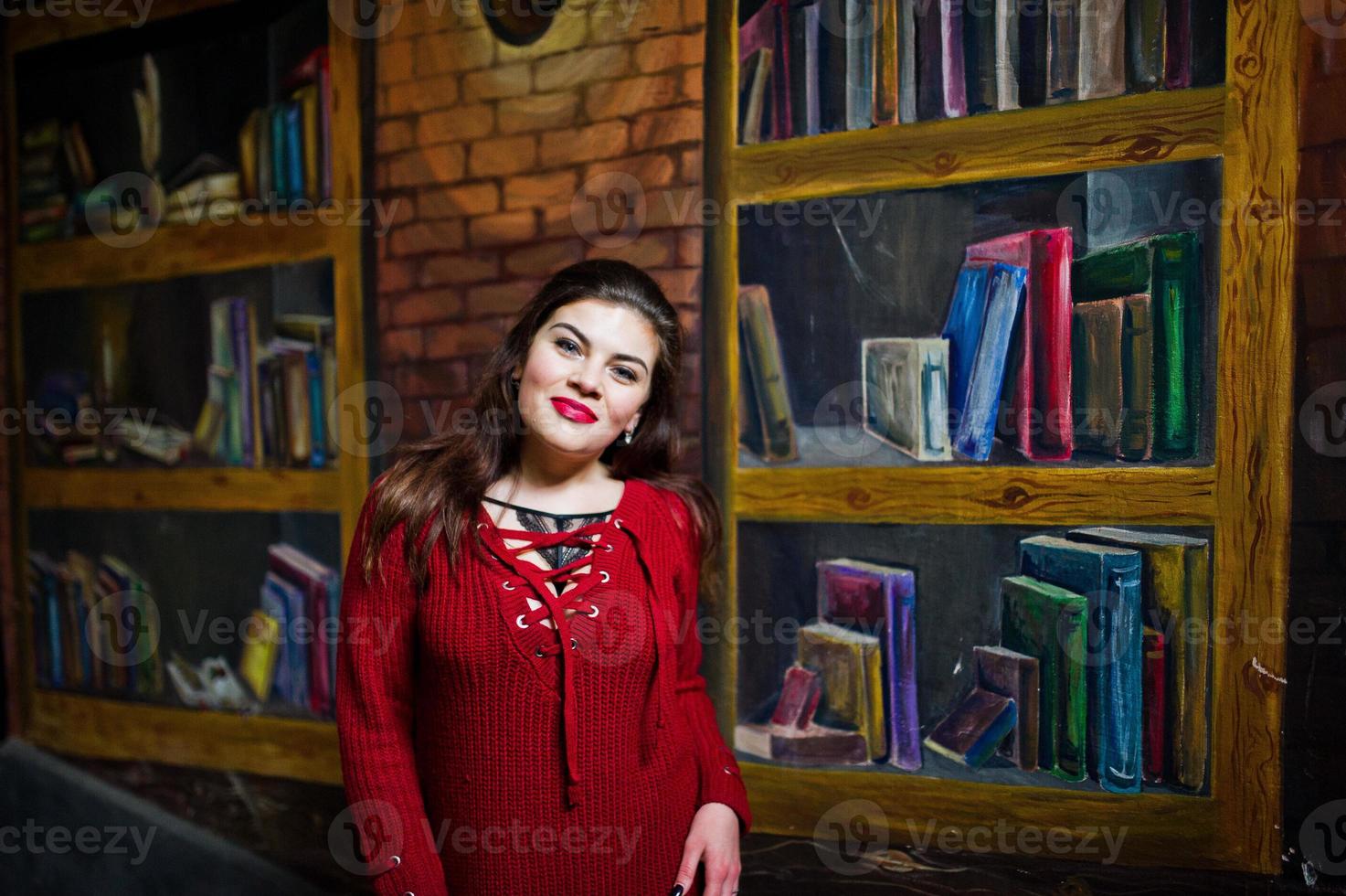 Brunette plus size model against wall like library. photo