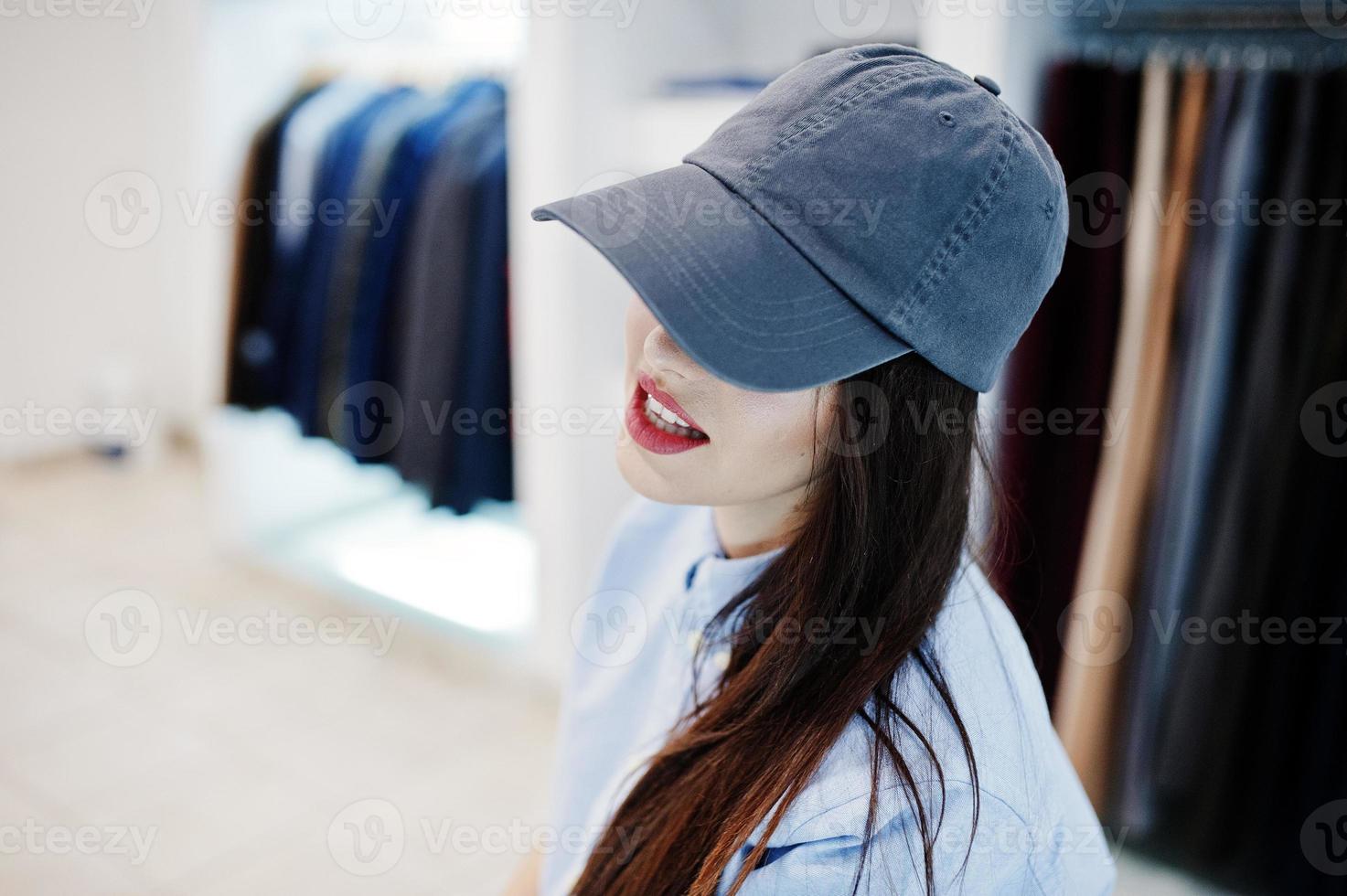 hermosa chica morena en la boutique de la tienda de ropa en ropa casual y gorra. foto