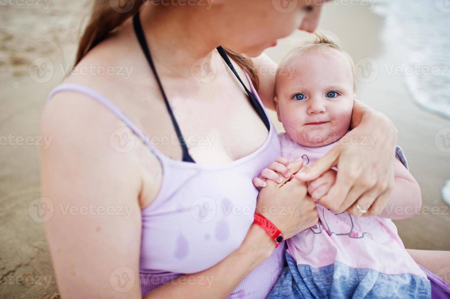 Summer vacations. Parents and people outdoor activity with children. Happy family holidays. Pregnant mother with baby daughter on sea sand beach. photo