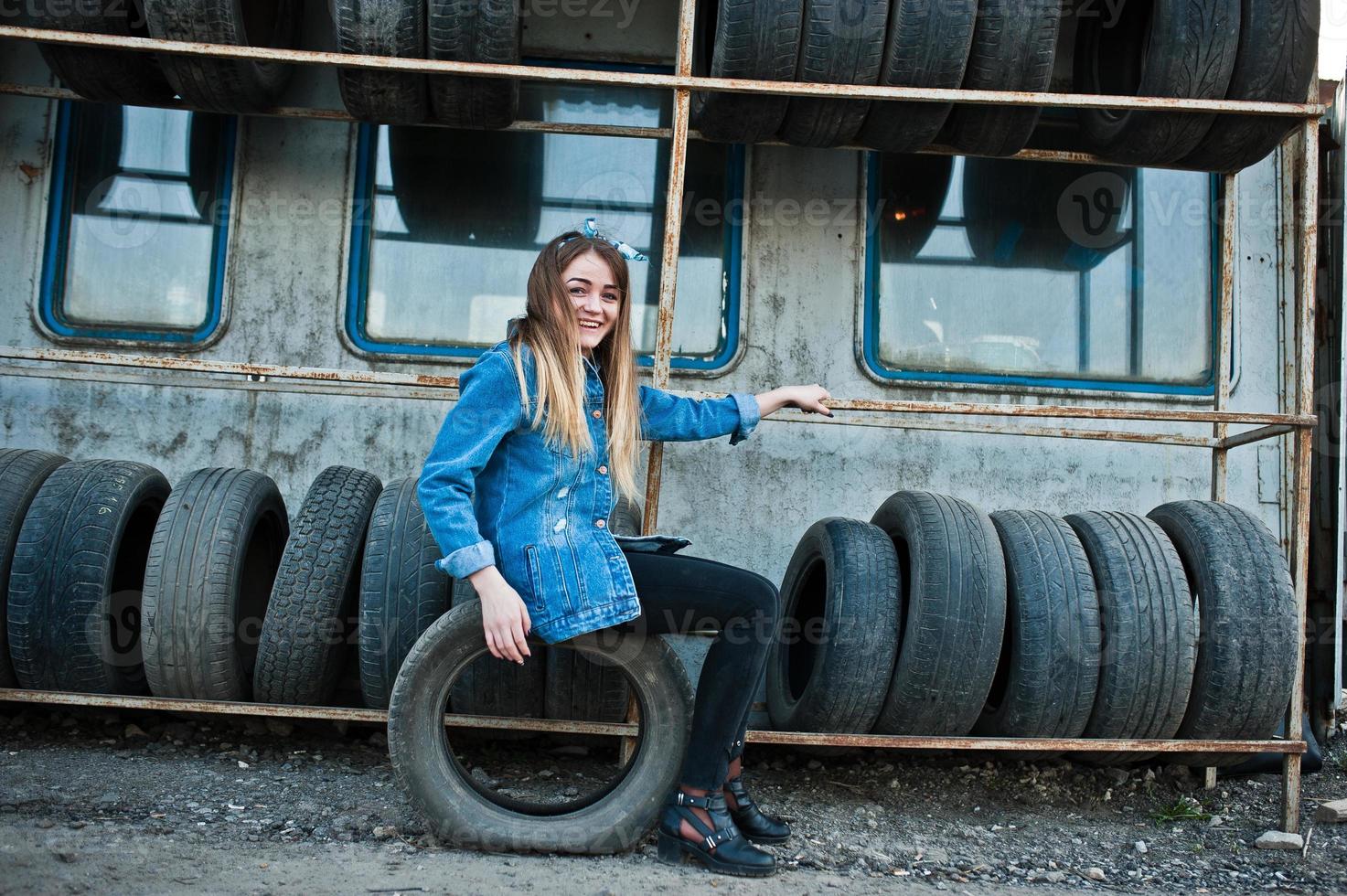 Young hipster girl in jeans jacket and head scarf at tire fitting zone. photo