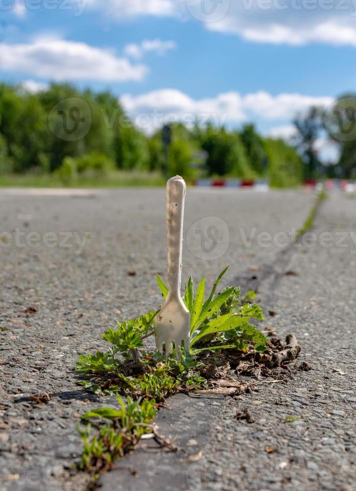 Fork stuck into weeds growing in a crack in tar photo