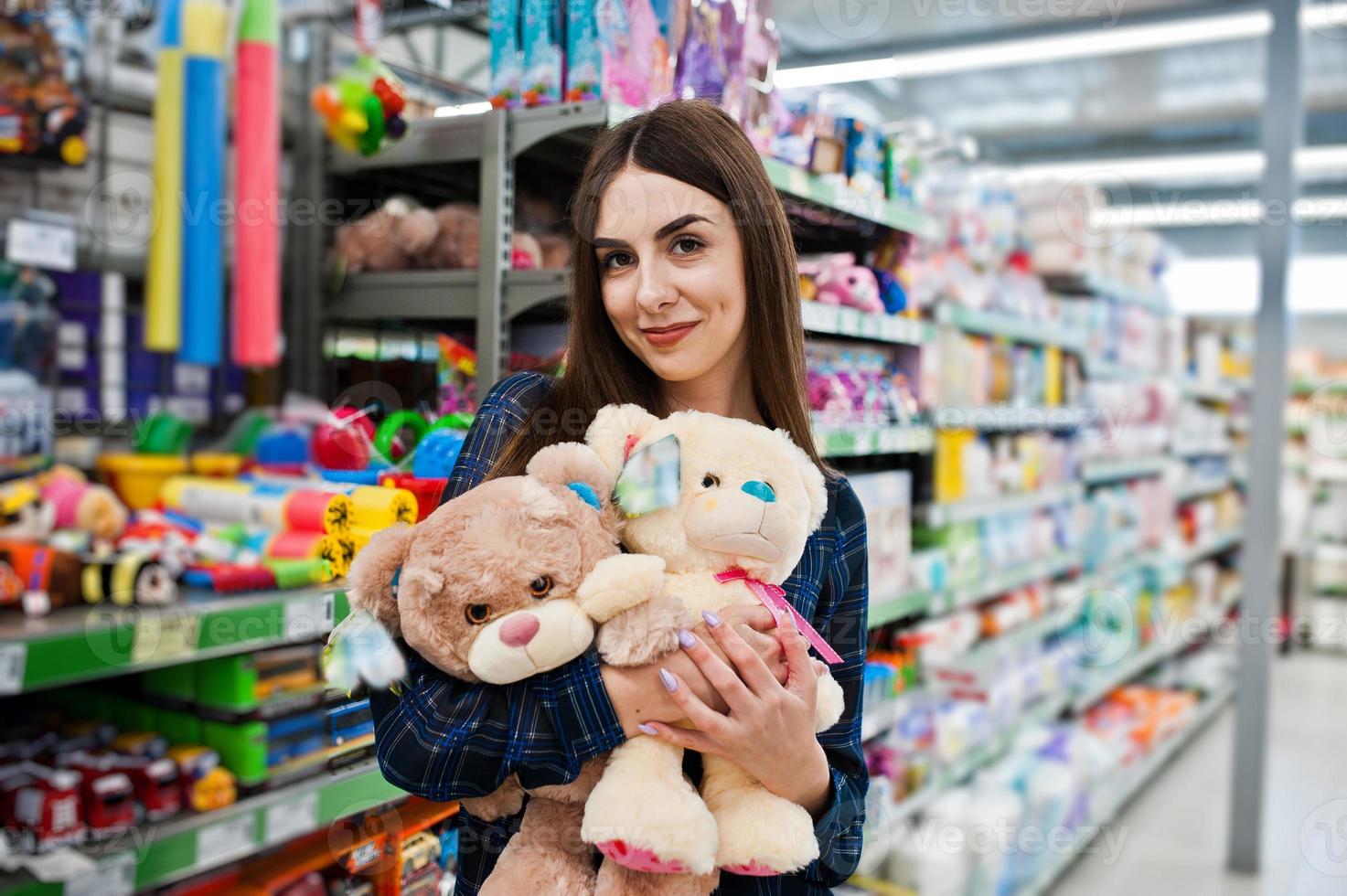 mujer de compras mirando los estantes del supermercado. retrato de una niña en una tienda de mercado con pequeños juguetes blandos. foto