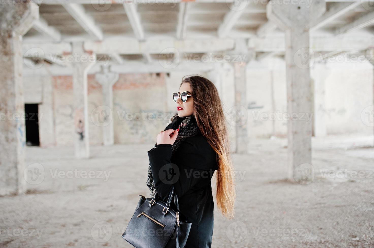 Brunette stylish casual girl in scarf and handbag against abandoned factory place. photo