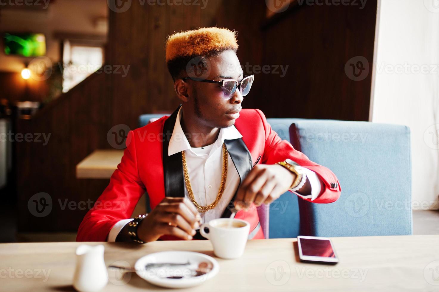 Fashion african american man model at red suit, with highlights hair and sunglasses sitting at cafe with coffee. photo