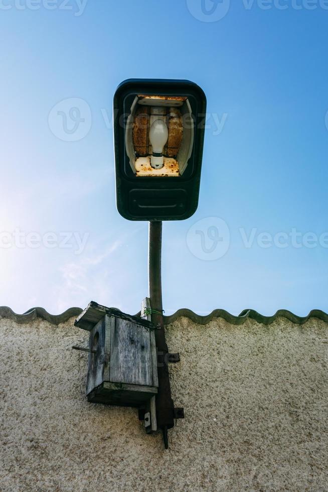 lámpara antigua con techo de casa y caja de pájaros foto