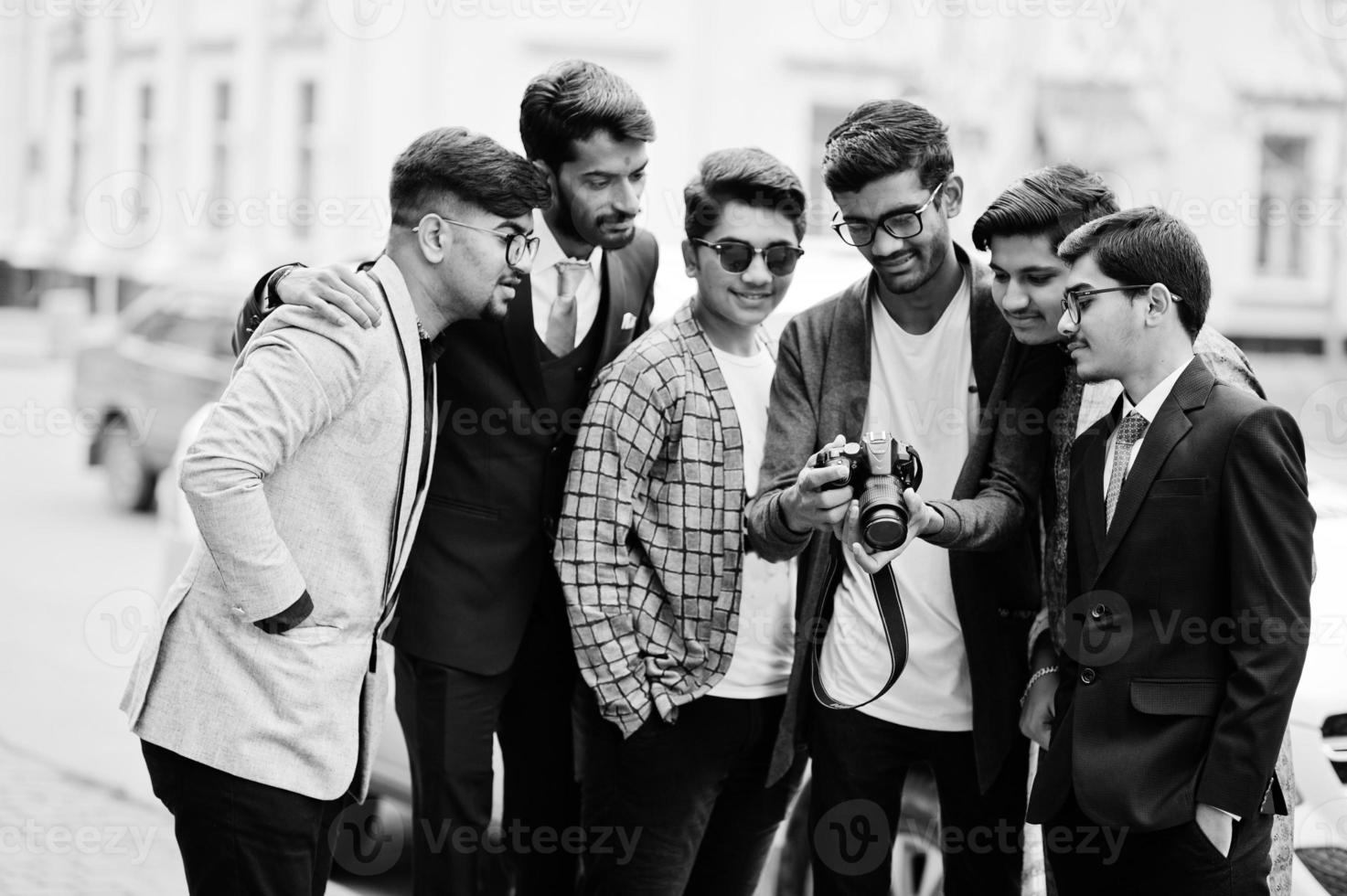 Group of six south asian indian mans in traditional, casual and business wear. Asia tourists looking at the dslr photo camera.