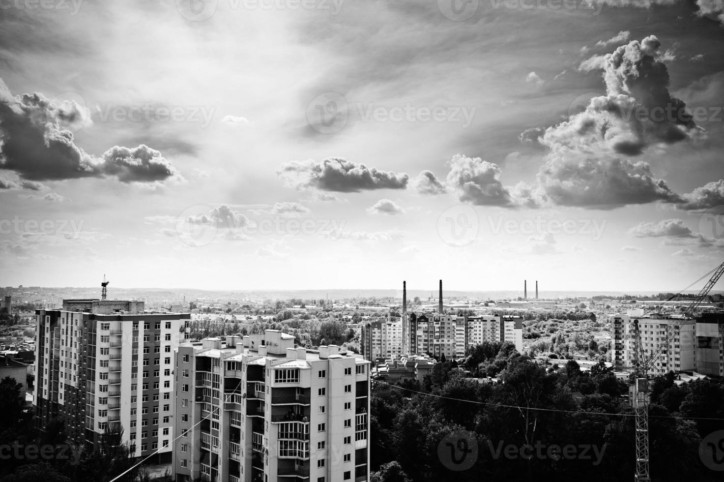 Black and white photo of city view roofs and cloudy sky.