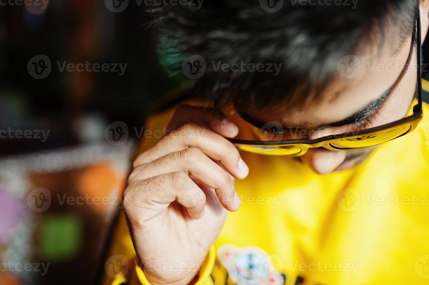 Cierra el retrato de un hombre asiático con gafas de sol y sudadera amarilla. foto