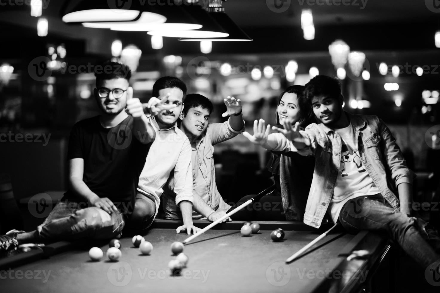 Group of stylish asian friends wear on jeans playing pool billiard on bar. photo